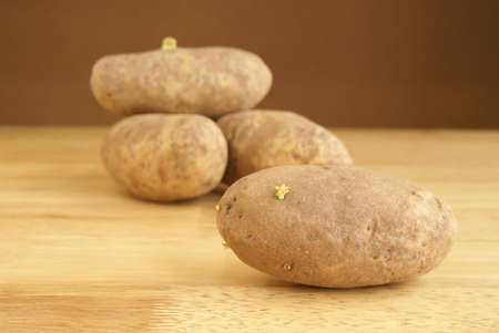 Raw whole potatoes on a wooden butcher block tableの写真素材