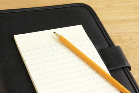 Pencil and Notepad laying on a black leather appointment book or portfolioの写真素材