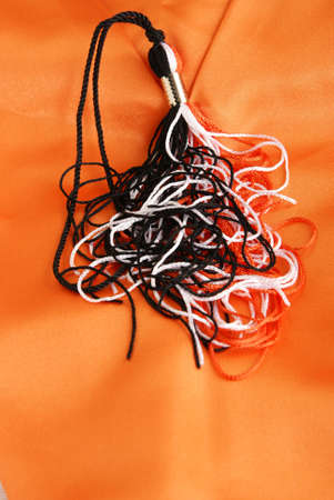 Scattered Graduation tassle cords in black, orange and white on orange silkの写真素材