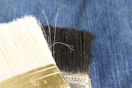 Two paint brush heads closeup on blue denim background