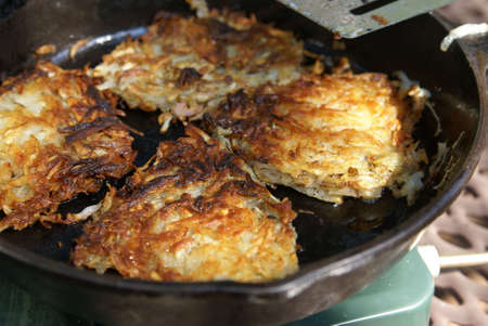 Home made shredded potato hash browns cooking in a cast iron skillet