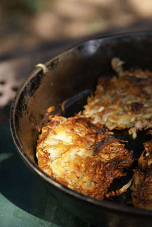 Hash brown potatoes cooking in an iron skillet outdoors. Vertical format with blurred background.の写真素材