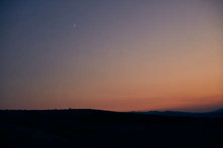 beautiful sunset and new moon on the background of hillsの写真素材