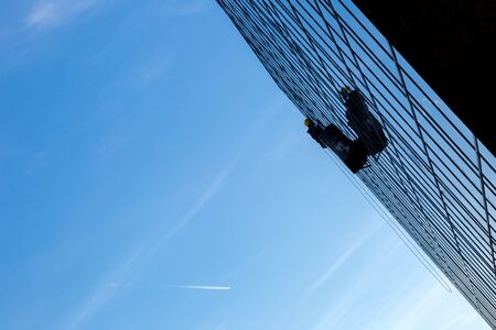 Window cleaner's on platform cleaning windows in modern building
