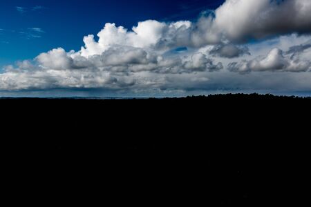 Dramaic clouds on blue sky over dark low horizonの写真素材