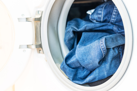 Open door in washing mashine with jeans inside close upの写真素材