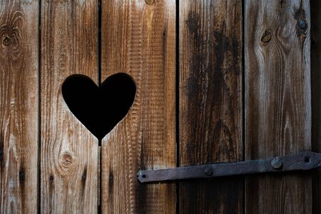 Black heart cut in old vintage rustic wooden timbers as a backgroundの写真素材