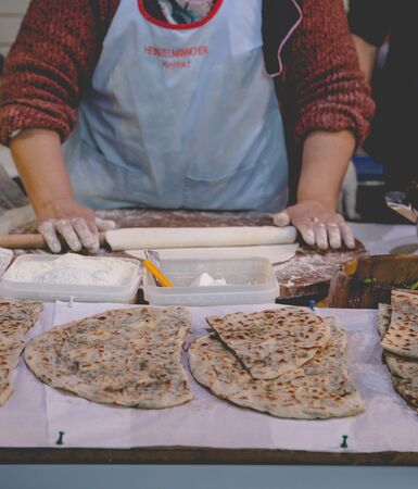 Older woman kneading a flat naan bread at stall on the traditional food market in Londonの写真素材