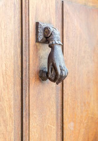 Old rustic vintage style door knocker in woman hand shape with ring. Close up view with ornament details. Horizontal full frame cropの写真素材