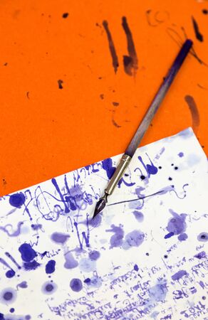 Old simple vintage wooden fountain pen on wooden table in school with page of paper full of blue ink splashes. Close up full frame viewの写真素材