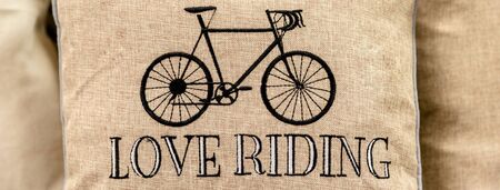 Black sport retro bike embroidered on gold cushion with love riding writing. Panoramic email header...