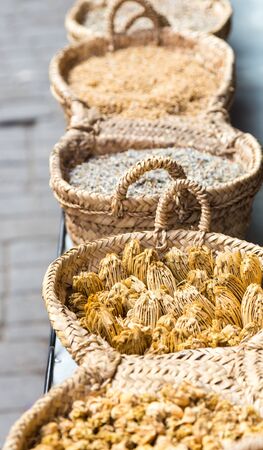 Dry herbs in handmade braided basket in traditional Arabic farmacy stall for sale on local market. Vertical full frame close up crop.の写真素材