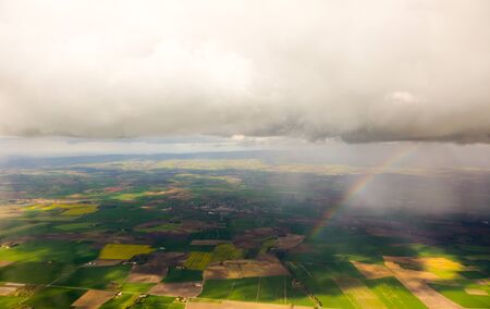 Rainbow under clouds over aerial view of English fields and meadows. Horizontal view with central...