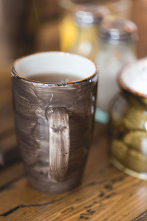 Clay brown cup of dark filtered coffee on wooden rustic table. Close up vertical composition, shallow depth of field.の写真素材