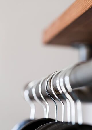 Black hangers hanged on rustic poll under shelf in wardrobe. Vertical composition with selective...