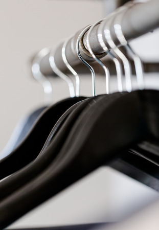 Black hangers hanged on rustic poll under shelf in wardrobe. Vertical composition with selective focus on wire, shallow depth of fieldの写真素材