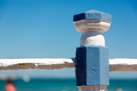 White and blue metal poll by sea promenade fence in Weymouth. Close up detailed minimalistic...