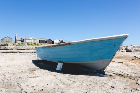 Old vintage traditional fishing blue boat on Isle of Portland rocks, UK. Low wide angle viewの写真素材