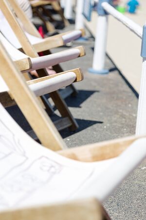 Traditiona wooden deck chairs along promenade
. Vertical close up crop