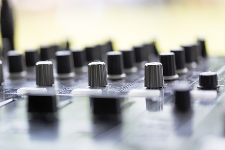 Dj works on mix console at outdoor party. Close up shot, focus on urn buttons and dj hands.