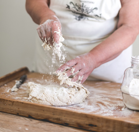 Grand mother makes traditional dumplings. Close up on working hands. Square crop, saturated faded...