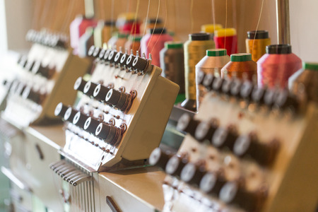 Textile sewing machines in factory hall. Horizontal crop with shallow depth of field