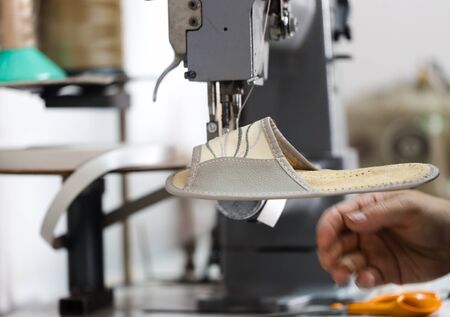 Woman shoemaker sewign flip flops on dedicated machine. Close up crop with selective focus working...
