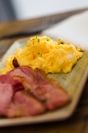 Delicious hot scrambled eggs with pan fried bacon on plate. Vertical macro crop.の写真素材