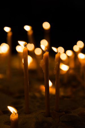 Slow burning wax candles in church as a symbol of death memory. Dark macro close composition with shallow depth of field.の写真素材