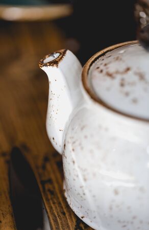 Old styled earthenware tea pot in shabby chic style close up on old wooden rustic table. Vertical cropの写真素材