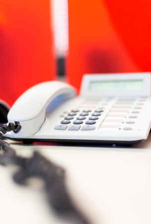 Bright white office telephone station on desk. Close up macro view, low angle perspectiveの写真素材