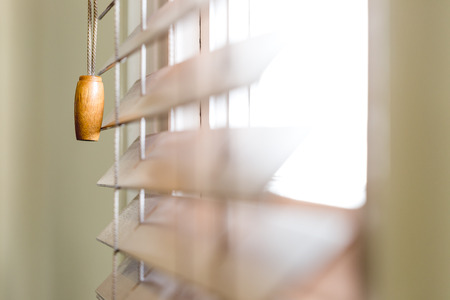 Wooden window blinds partially closed with bright light going through. Close up detailed crop, side angle perspective, shallow depth of fieldの写真素材