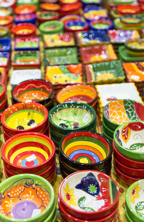 Colourful hand painted bowls and pots for sale arranged in rows on market stall. Full frame vibrant colours background vertically cropの写真素材