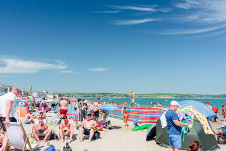 Weymouth beach is full of beach people enjoying hot weather. Weymouth 18.07.2021のeditorial素材