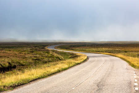 Single twisty, wavy, serpentine road with mist above in NC500, Scotlandの写真素材
