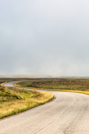 Single twisty, wavy, serpentine road with mist above in NC500, Scotlandの写真素材