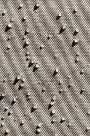 Waterdrops on waterproof fabric in bright daylight with strong shadows. Full frame shot with large...