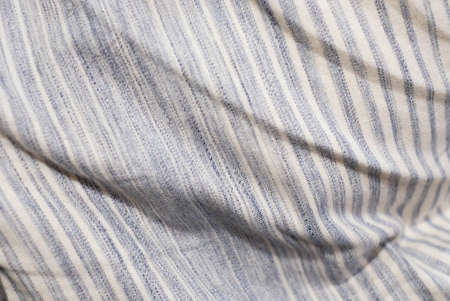 Blue stripe pattern on beige fabric texture. Closeup view of creased fabric background.