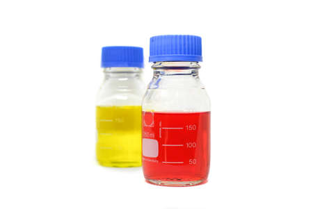Glass chemistry bottles with red and yellow liquid or solvent used for measurements on white background. A science lab equipment for lab testing and experiment. Selective focus with blurred backgroundの写真素材