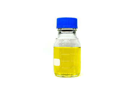 A glass chemistry bottle with yellow liquid or solvent used for measurements on white background. A science lab equipment for lab testing and experiment.の写真素材