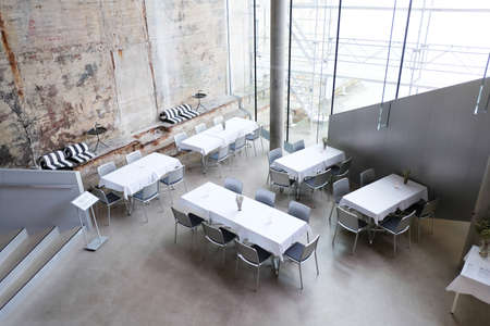 Dining sets in a cafe inside M/S Maritime Museum of Denmark in HelsingÃ¸r,Denmark.A contrast between modern furniture and old dock walls.のeditorial素材