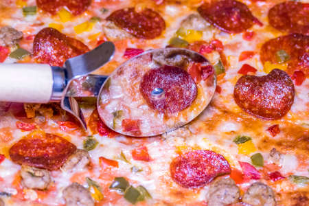 Close up view of a delicious pizza being cut into slicesの写真素材