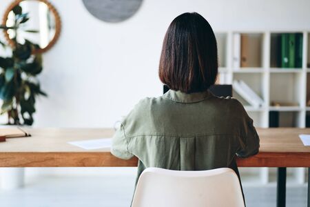 Young woman sitting at wooden desk and working in officeの写真素材