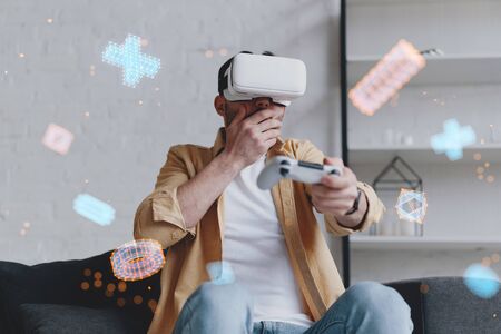 Emotional man in VR glasses playing video game with joystick, innovation hologramの写真素材