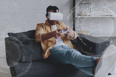 Emotional man in VR glasses playing video game with joystick, innovation hologramの写真素材