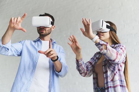 Closeup view of young concentrated couple wear. Virtual reality goggles headset glasses. Happy...