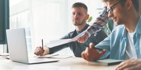 Two man and woman working together while sitting at their working place in office