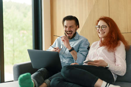 Smiling family couple laughing using computer and smartphone