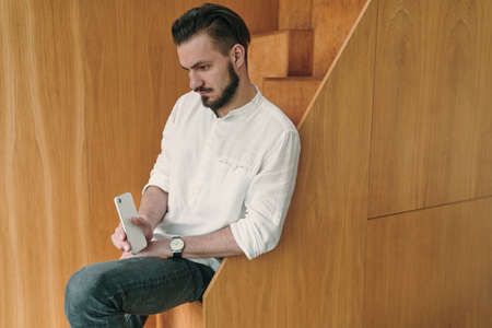 Portrait of young businessman holding smart phone and looking at screen