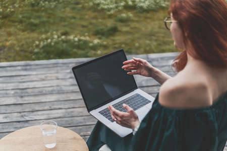 Successful woman looking at laptop monitor, holding online video call with colleaguesの写真素材